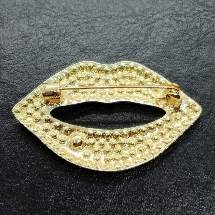 détail de l’épingle de fixation, broche lèvres rouges en strass fantaisie, finition scintillante.
