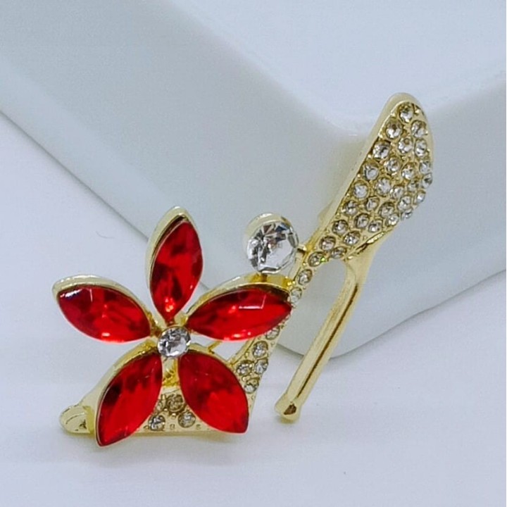 broche chaussure aux talons hauts, détails des strass et des pierres qui captent la lumière sous différents angles.