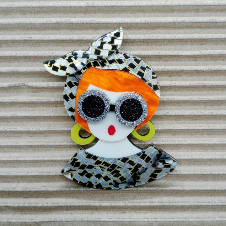 Broche en acrylique femme rousse, détail des lunettes grises pailletées