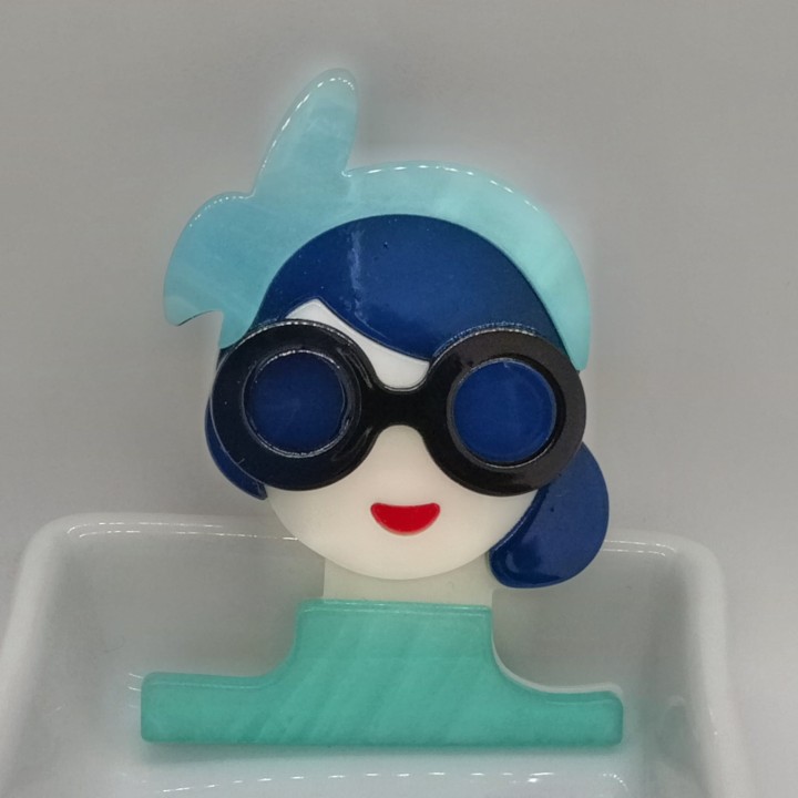 broche en acrylique femme avec des lunettes rondes noires, parfaites pour un look rétro-chic.