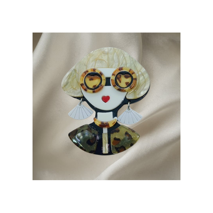 Détail de la broche femme blonde, lunettes écaille de tortue et boucles d'oreilles blanches