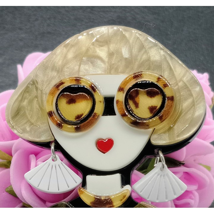 Broche acrylique femme blonde, détail des lunettes rondes écaille de tortue, parfaites pour un look rétro-chic.